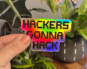 May include: A holographic sticker with the text "Hackers Gonna Hack" in a pixelated font. The sticker is rainbow colored and has a black outline.