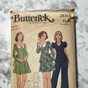 Puede incluir: Sobre de patrón de costura vintage para un vestido y pantalones. El patrón es para las tallas 5/6 a 13/14. El sobre presenta tres ilustraciones de mujeres que llevan las prendas. El vestido se muestra en tela estampada verde y azul. Los pantalones se muestran en tela azul. El patrón es de Butterick y es el número 3015.