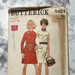 May include: Vintage sewing pattern for two dresses, one red and one white, with a size 14 and bust size 36. The pattern is from Butterick and is number 5424. The pattern is 75 cents.