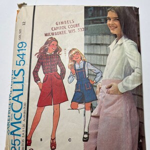 May include: A vintage sewing pattern for girls' culottes with a detachable bib and blouse. The pattern is from McCall's and is number 5419. The pattern is for size 12 and is available from Gimbels Capitol Court in Milwaukee, Wisconsin.