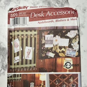 May include: A sewing pattern for desk accessories, including noteboards, blotters, and more. The pattern includes instructions for making a striped fabric noteboard, a floral fabric noteboard, and a grid-style noteboard. The pattern also includes instructions for making a lampshade and a desk organizer.