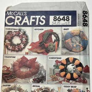 Peut inclure: Un livret de modèles vintage McCall's Crafts avec une image de couverture représentant une variété de couronnes faites à la main. Le numéro du modèle est 8648 et le prix est de 4,25 $. Les couronnes sont décorées de différents thèmes, notamment Noël, la Saint-Valentin, Pâques et un ours en peluche.