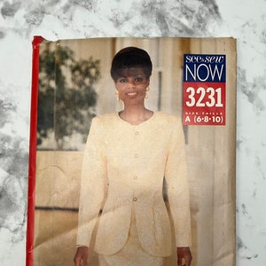 May include: A vintage sewing pattern for a cream-colored suit jacket and skirt. The pattern is from the see & sew NOW line and is size A (6-8-10). The pattern cover features a model wearing the suit.