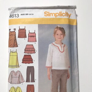 May include: Simplicity sewing pattern number 4613, size BB 5, 6, 7, 8. The pattern includes instructions for making a variety of girls' clothing, including a dress, a top, a skirt, and pants. The pattern is illustrated with a young girl wearing a white top with red polka dots and brown and white checkered pants.