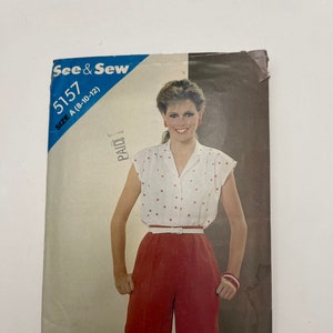 May include: A vintage sewing pattern envelope featuring a woman wearing a white polka dot blouse with red shorts and a white belt. The pattern number is 5157 and the size is A (8-10-12).
