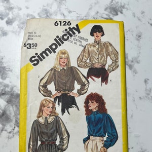 May include: Simplicity sewing pattern number 6126 for a blouse with a collar and long sleeves. The pattern is for sizes 10, 12, and 14. The pattern is available for $3.50.
