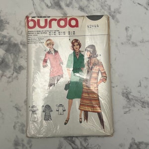 May include: A Burda sewing pattern for a dress with two different styles. The pattern is for sizes 42 and 44. The pattern includes instructions for making a green dress with a belt and a striped dress with a collar.