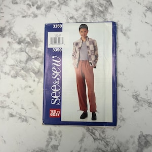 May include: A sewing pattern titled "3359" featuring a person modeling a jacket and pants. The jacket has a checkered pattern, and the pants are a reddish-brown color. The pattern's brand is "see & sew" with the text "YES! it's easy".