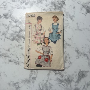 May include: Vintage Simplicity printed pattern 3702 for aprons. The pattern features illustrations of aprons with floral, gingham, and striped designs. The pattern includes the text "One Size" and "Printed Pattern 45c".
