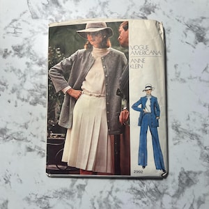 May include: Vintage Vogue Americana Anne Klein sewing pattern. The cover features a woman in a gray jacket, white skirt, and hat. The pattern includes a drawing of a blue suit. The pattern number is 2992.