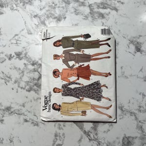 May include: A vintage Vogue basic design sewing pattern. The pattern features illustrations of women's clothing designs, including suits and dresses. The cover is white with the Vogue logo and pattern number visible. The background is a light gray.