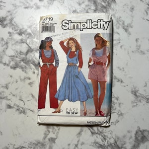 Puede incluir: Patrón de costura Simplicity número 9719, con tres estilos diferentes de petos. El patrón incluye instrucciones para hacer un mono rojo, una falda vaquera azul con petos y unos pantalones cortos de petos de rayas rojas y blancas. El patrón está etiquetado como "Fácil de coser".