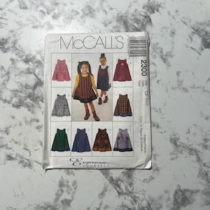 May include: A sewing pattern for a girl's dress. The pattern includes instructions for making a variety of styles, including a plaid dress, a denim dress, and a floral dress. The pattern is for sizes 4, 5, and 6. The pattern is from McCall's and is called "Express Yourself".