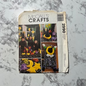 Puede incluir: Un patrón de costura de McCall's Crafts para un disfraz de bruja de Halloween y decoraciones. El patrón incluye instrucciones para hacer un sombrero de bruja, una capa de bruja y una escoba de bruja. El patrón también incluye instrucciones para hacer un caldero de bruja, una telaraña de bruja y una calabaza de bruja. El número del patrón es 2990.