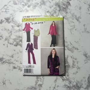 May include: A Simplicity sewing pattern for women's clothing. The pattern includes three different styles: a long-sleeved top with a ruffled collar, a long-sleeved top with a scoop neck, and a long-sleeved jacket with a shawl collar. The pattern is for sizes 10, 12, 14, 16, and 18.