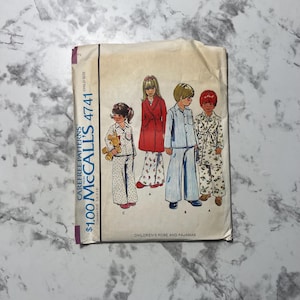 May include: A vintage sewing pattern for children's pajamas and a robe. The pattern is from McCall's and is number 4741. The pattern shows three children wearing the pajamas and robe. The pajamas are striped and floral patterned. The robe is red with a floral pattern.
