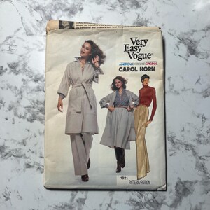 May include: Vintage Very Easy Vogue sewing pattern featuring designs by Carol Horn. The pattern envelope shows illustrations of a woman in a belted coat, pantsuit, and a long-sleeved top with wide-leg pants. The envelope is off-white with black text.