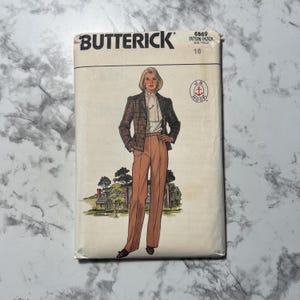 Könnte beinhalten: Vintage-Nähmuster-Umschlag für ein Damen-Hosen- und Jacken-Set. Das Muster ist von Butterick, Musternummer 6869, Größe 16. Das Model trägt eine karierte Jacke und eine braune Hose. Das Muster ist für ein J.G. Hook-Design.