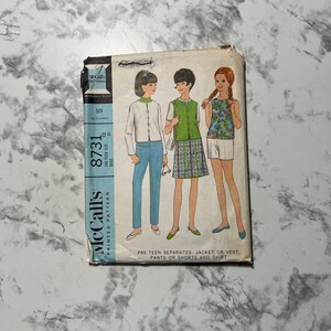 Puede incluir: Patrón de costura vintage McCall's 8731. El patrón presenta ilustraciones de conjuntos para preadolescentes: una chaqueta o chaleco, pantalones, pantalones cortos y una falda. El patrón incluye la talla 12, con una medida de busto de 79 cm. La portada tiene un esquema de color azul y blanco.
