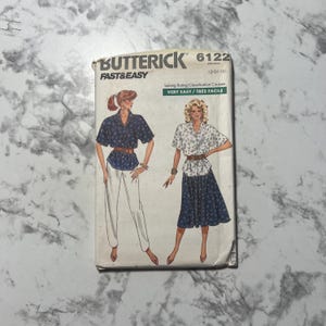 May include: A vintage Butterick sewing pattern, model 6122, showing illustrations of two outfits: a blouse and trousers, and a blouse and skirt. The pattern is labelled "Fast & Easy" and includes the text "Very Easy / Tres Facile".