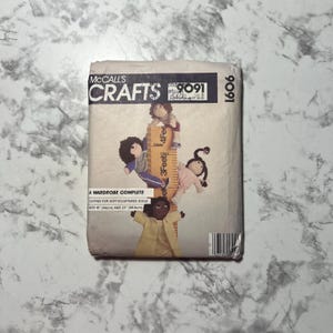 May include: A McCall's Crafts sewing pattern for making clothes for soft sculpted dolls. The pattern number is 9091 and the pattern is for dolls that are 18 inches (46 cm) and 23 inches (58.5 cm) tall.