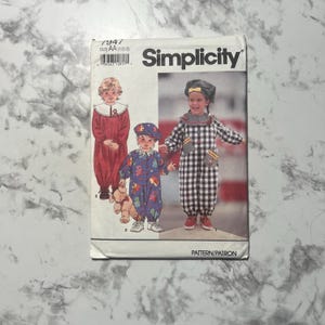 May include: Simplicity sewing pattern with children's clothing designs. The pattern shows illustrations of three outfits: a red jumpsuit, a blue patterned jumpsuit, and a black and white checkered jumpsuit. The pattern is size AA (1/2-2).