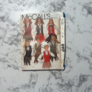 May include: Vintage McCall's sewing pattern featuring illustrations of women's vests and blouses. The pattern cover displays a variety of designs in red, black, and brown. The pattern number is 8117.