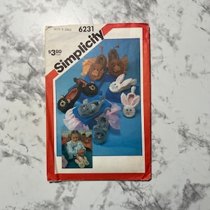 May include: Simplicity sewing pattern number 6231 for boys and girls. The pattern is for making animal slippers. The pattern shows a variety of animal slippers, including a lion, a bear, a bunny, and a cat. The pattern is $3.00.