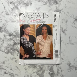 May include: A McCall's Crafty sewing pattern for a jacket with a size range of 6-8-10-12-14. The pattern is for a white jacket with a decorative button closure and a black jacket with a ruffle detail. The pattern number is M5760.