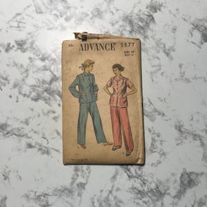 May include: Vintage sewing pattern envelope for a pajama set. The pattern is from Advance, pattern number 5877, size 16, bust 34. The envelope shows two women wearing the pajamas, one in blue and one in pink.