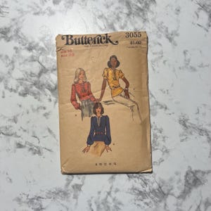 May include: A vintage Butterick sewing pattern, size 16, featuring illustrations of blouses. The pattern envelope is tan with the text "Butterick" and "THE FASHION ONE". The bust size is 33 inches. The price is $1.00.