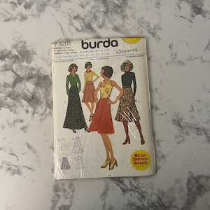 May include: A vintage Burda sewing pattern for a skirt. The pattern is for sizes 10-12-14, 16-18-20, and 36-38-40. The pattern includes three different skirt styles, each with a different print. The pattern is labeled "Three-size pattern" and "Mit der Zweifach-Garantie".
