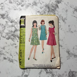 May include: Vintage McCall's sewing pattern for a pre-teen dress or jumper in two versions and a blouse. The pattern number is 8772 and the bust size is 29 inches.