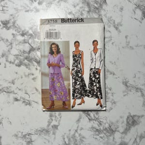 May include: A Butterick sewing pattern packet featuring three dress designs. The packet shows a woman in a purple skirt and jacket, and two other dresses with floral patterns. The packet has the number 3758 printed on it.