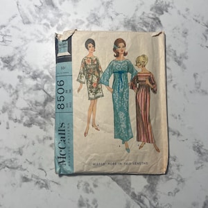 May include: A vintage McCall's sewing pattern envelope 8506 for a robe in two lengths. The front features illustrations of three figures wearing different robe styles, including a floral print, a solid blue with white floral detail, and a striped design.