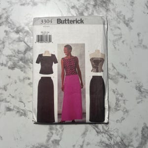 以下が含まれることがあります： Butterickのソーイングパターン、番号3304。四角いネックのトップスとスカート、柄物のトップスとピンクのスカート、ストラップレスのトップスとスカートのイラストが特徴です。パターンにはサイズ20-22-24が含まれています。
