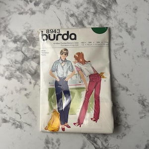 May include: A Burda sewing pattern for pants, with a model wearing a pair of blue jeans and a model wearing a pair of red pants. The pattern number is 8943. The pattern sizes are 152, 158, 164, and 170. The corresponding sizes are 12, 10 jun, 11 jun, and 13 jun.