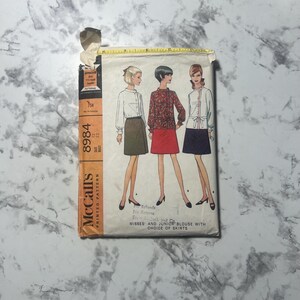 May include: Vintage McCall's printed sewing pattern, featuring illustrations of three women in blouses and skirts. The pattern includes options for misses' and junior blouses with a choice of skirts. The pattern number is 8984.