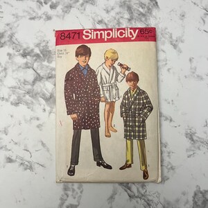 May include: Vintage Simplicity sewing pattern number 8471 for a boy's robe. The pattern is for sizes 16 with a 34 inch chest. The pattern shows three boys wearing different robes. One robe is black and white, one is white, and one is black and plaid.
