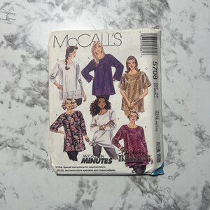 May include: McCall's sewing pattern 5708 for women's tops. The pattern features various top designs, including long-sleeved and short-sleeved options. The pattern includes the text "McCall's in Minutes" and "Extra: Special instructions for sequined fabric".