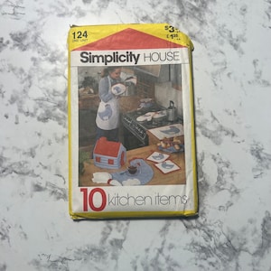May include: A Simplicity House sewing pattern for 10 kitchen items, including an apron, pot holder, and placemats. The pattern features a blue and white chicken design and is labeled "124".