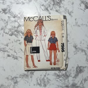 May include: McCall's sewing pattern number 7595 for girls' clothing. The pattern includes a white jacket with a red and white striped shirt, a white skirt with a plaid shirt, and red shorts with a blue and white patterned shirt. The pattern is for sizes C 6-8.