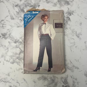 Puede incluir: Patrón de costura vintage "See & Sew 5142" con una mujer con blusa blanca, pantalón negro y pajarita. El patrón incluye tallas A (8-10-12). La imagen está sobre un fondo de papel desgastado y envejecido.