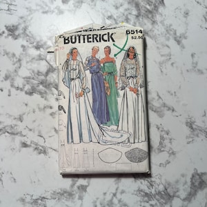 May include: A vintage sewing pattern for four different dresses. The pattern is from Butterick and is number 6514. The dresses are all long and flowy, with different necklines and sleeves. The pattern is printed on white paper with black and green ink.
