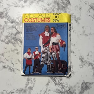May include: A vintage McCall's Costumes sewing pattern featuring pirate costumes. The pattern cover displays illustrations of pirate outfits with red, white, and black color schemes. The text "EASY TO SEW" is visible.