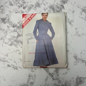 May include: A vintage sewing pattern for a skirt and blouse. The pattern is for sizes 12-14-16 and is called "Stitch 'N Save" 8277. The pattern shows a woman wearing a blue skirt and blouse with a white collar.