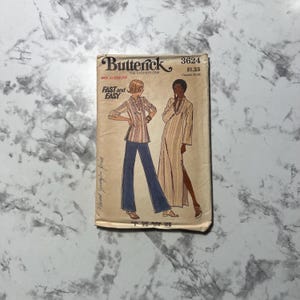May include: Vintage sewing pattern envelope for a dress and pants. The pattern is by Butterick, number 3624, and costs $1.25. The envelope features a line drawing of two women wearing the garments. The dress is a long, flowing style with a slit up the side. The pants are wide-legged and have a high waist.
