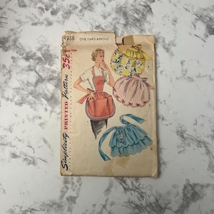 May include: Vintage Simplicity sewing pattern for one-yard aprons. The pattern is printed on a white paper with a red, white, and blue color scheme. The pattern includes three different apron styles, each with a different design. The pattern number is 4938 and the price is 35 cents.
