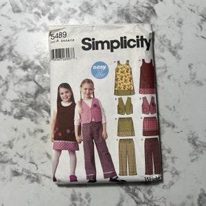 May include: Simplicity sewing pattern number 5489 for girls' clothing. The pattern includes a dress, vest, skirt, and pants. The pattern is labeled "easy to sew".