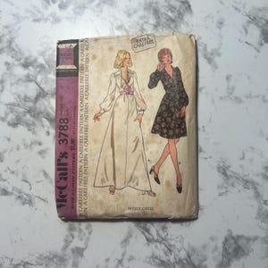 Puede incluir: Patrón de costura vintage McCall's para un vestido, con dos modelos que llevan diferentes estilos del vestido. El número del patrón es 3788 y el precio es de $1.00. El patrón está etiquetado como "Extra Carefree".